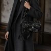 Model wearing a black pierced-stud crescent shoulder bag