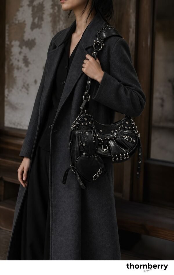 Model wearing a black pierced-stud crescent shoulder bag